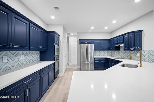 kitchen featuring sink, appliances with stainless steel finishes, tasteful backsplash, light hardwood / wood-style floors, and blue cabinets