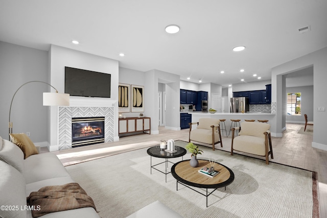 living room with a tile fireplace and light wood-type flooring