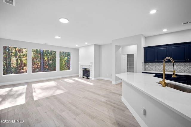 unfurnished living room featuring a premium fireplace, sink, and light wood-type flooring