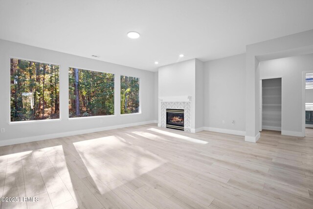 unfurnished living room with a tiled fireplace and light hardwood / wood-style flooring