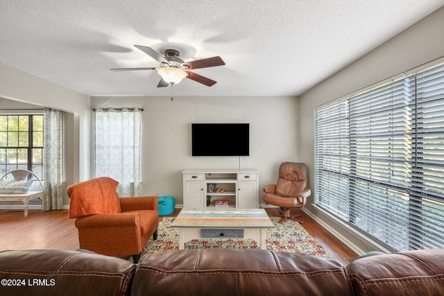 living room featuring ceiling fan, plenty of natural light, hardwood / wood-style floors, and a textured ceiling