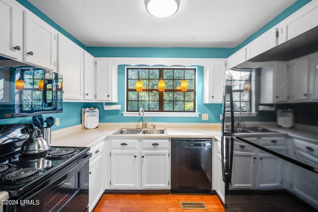 kitchen featuring sink, white cabinets, light hardwood / wood-style floors, and black appliances