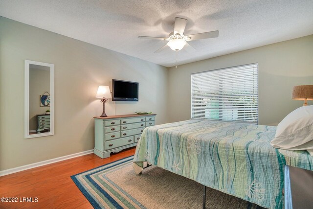 bedroom featuring wood-type flooring, a textured ceiling, and ceiling fan