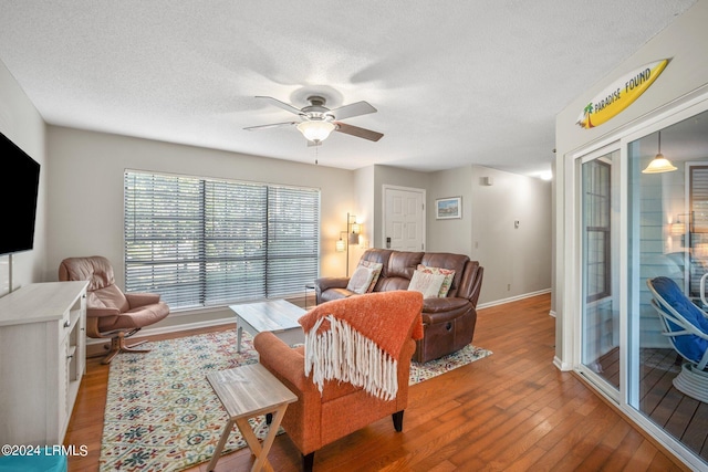 living room featuring a textured ceiling, wood-type flooring, and ceiling fan