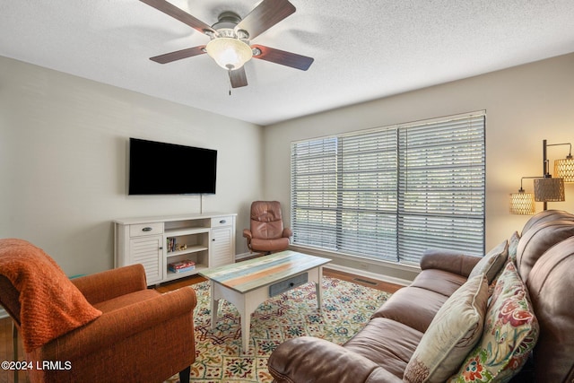 living room featuring a textured ceiling, wood-type flooring, and ceiling fan