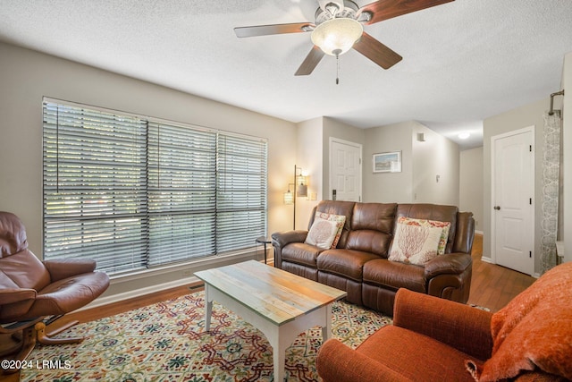 living room featuring a textured ceiling, ceiling fan, and light hardwood / wood-style flooring