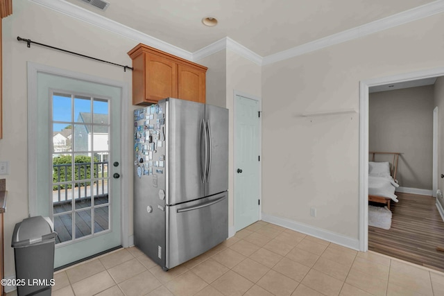 2176 Blakers Blvd, Okatie, SC 29909 - kitchen featuring light tile patterned floors, baseboards, freestanding refrigerator, brown cabinets, and crown molding
