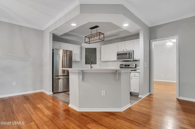 380 Marshland Rd Unit E26, Hilton Head Island, SC 29926 - kitchen with stainless steel appliances, white cabinets, decorative backsplash, light wood-style floors, and crown molding