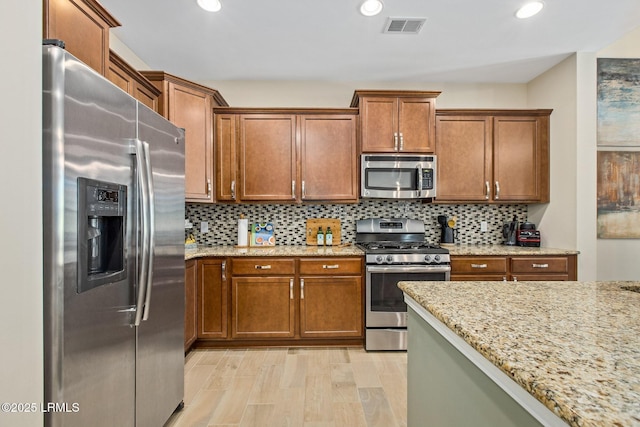 kitchen with light stone countertops, stainless steel appliances, and tasteful backsplash