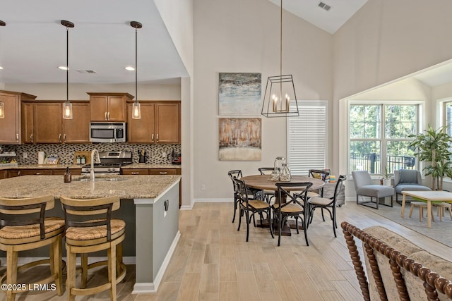 kitchen featuring brown cabinets, tasteful backsplash, light stone countertops, and appliances with stainless steel finishes