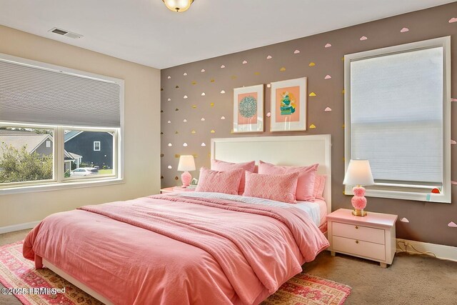 carpeted bedroom with wallpapered walls, baseboards, an accent wall, and visible vents
