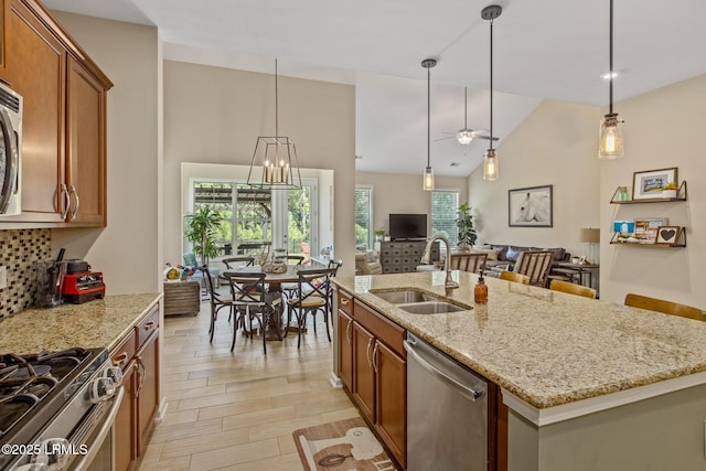 kitchen featuring open floor plan, a sink, light stone countertops, appliances with stainless steel finishes, and brown cabinets