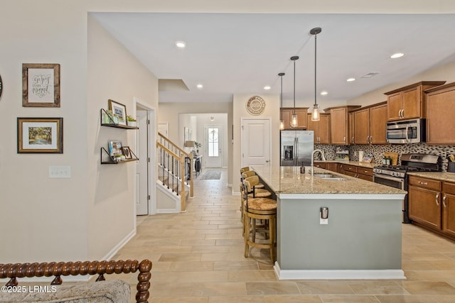 kitchen featuring brown cabinets, tasteful backsplash, a sink, and stainless steel appliances