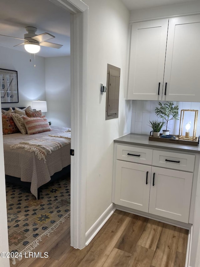 bedroom with wood-type flooring, electric panel, and ceiling fan