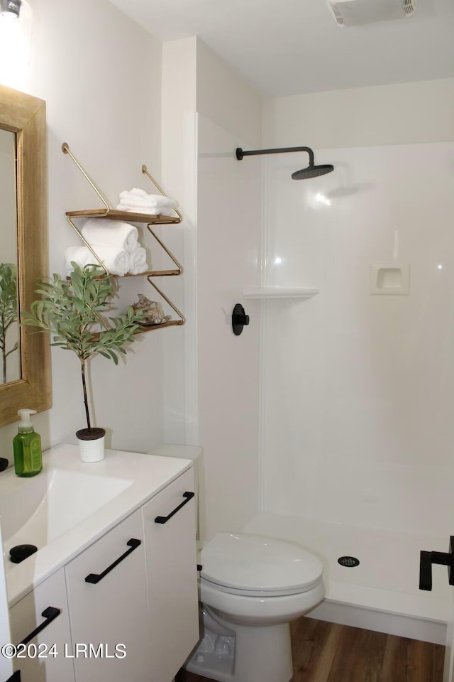 bathroom featuring vanity, a shower, wood-type flooring, and toilet