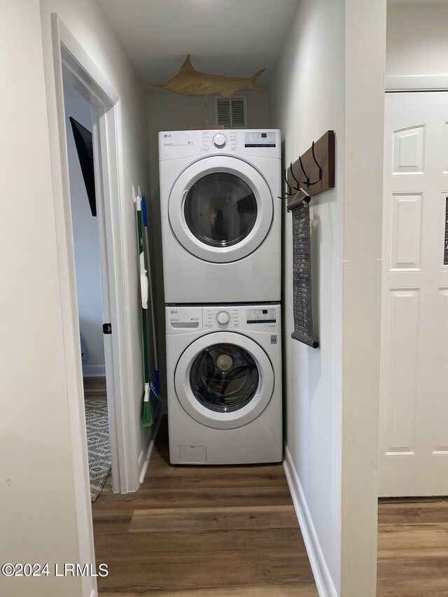 laundry area with stacked washer and dryer and dark hardwood / wood-style floors