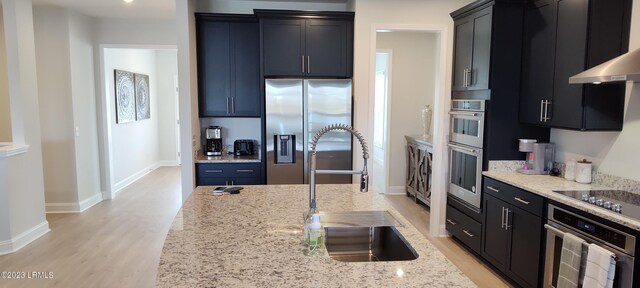 1272 Windswept Oak Ln, Beaufort, SC 29902 - kitchen with sink, light hardwood / wood-style flooring, stainless steel appliances, light stone counters, and wall chimney exhaust hood