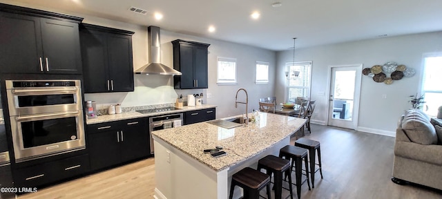 1272 Windswept Oak Ln, Beaufort, SC 29902 - kitchen featuring wall chimney exhaust hood, black electric cooktop, a kitchen breakfast bar, double oven, and a kitchen island with sink