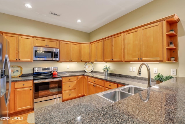 kitchen with stainless steel appliances, sink, and dark stone countertops