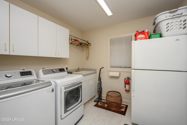 clothes washing area with cabinets, washer and clothes dryer, and sink