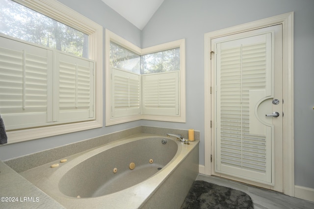 bathroom with lofted ceiling and a bath