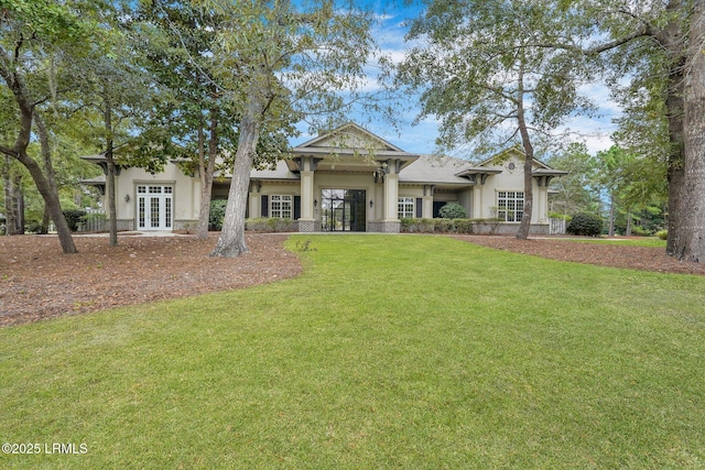 view of front of house with stucco siding, french doors, and a front yard