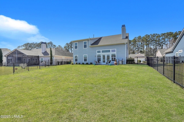 back of property with a fenced backyard, a chimney, and a yard