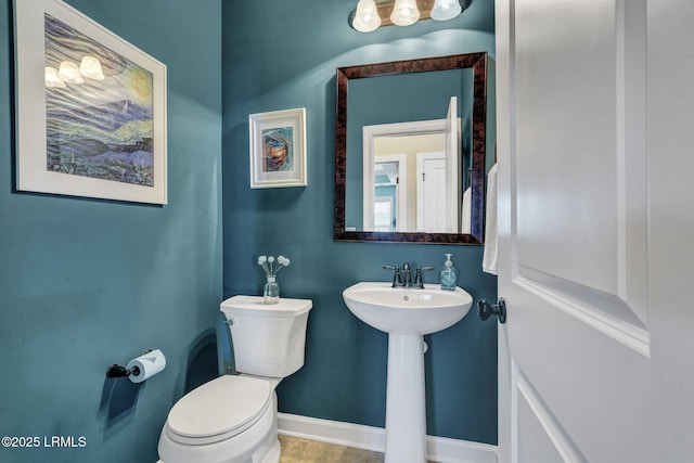 half bath featuring a sink, baseboards, and toilet