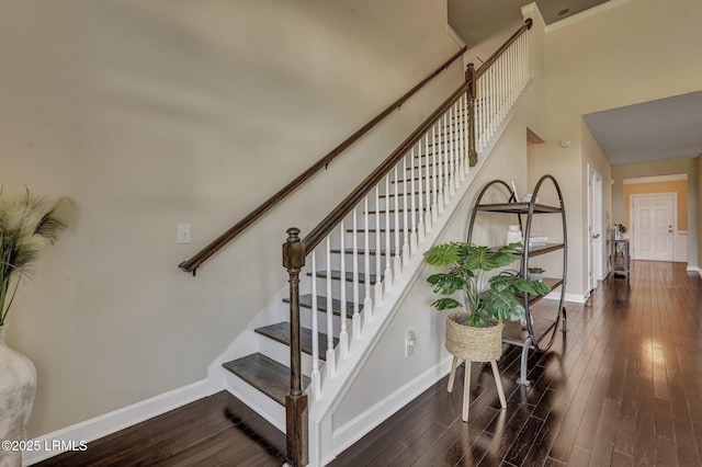 stairway featuring hardwood / wood-style flooring, baseboards, and a towering ceiling