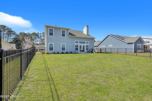 back of property featuring a lawn, a chimney, and a fenced backyard