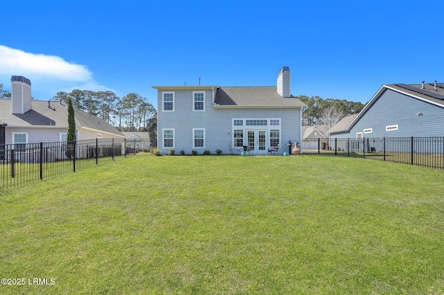 back of house with a yard, a fenced backyard, french doors, and a chimney