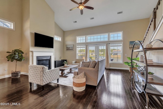 living area with a glass covered fireplace, dark wood-style floors, visible vents, and ceiling fan