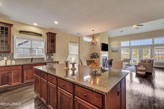 kitchen with a kitchen island, dark wood finished floors, ceiling fan with notable chandelier, open floor plan, and backsplash