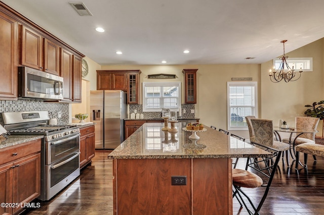 kitchen with visible vents, a notable chandelier, a center island, stainless steel appliances, and a breakfast bar area