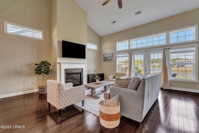 living area with dark wood finished floors, visible vents, baseboards, and a glass covered fireplace