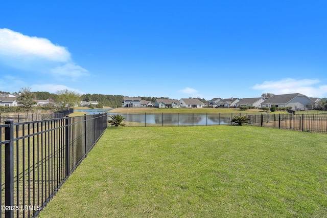 view of yard featuring a residential view, a fenced backyard, and a water view