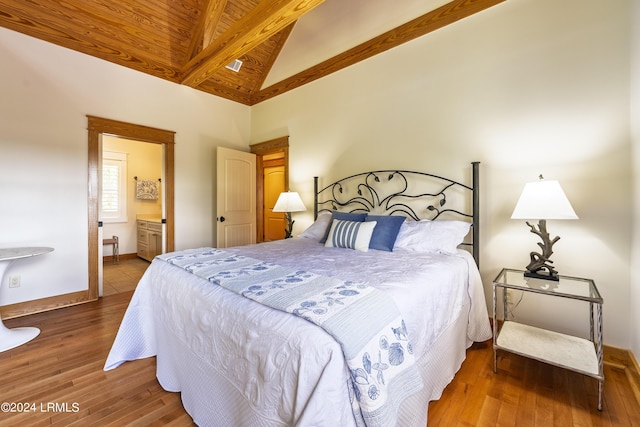 bedroom with beam ceiling, connected bathroom, wood finished floors, high vaulted ceiling, and baseboards