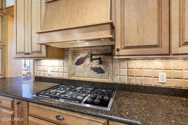 kitchen featuring decorative backsplash, dark stone countertops, and gas stovetop