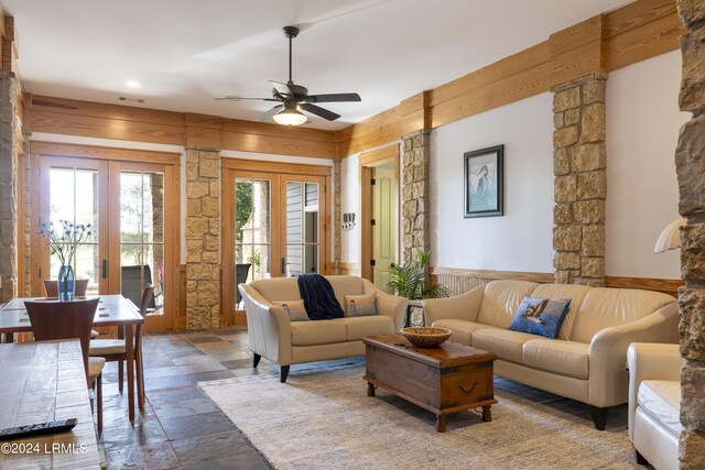 living area with ceiling fan, stone tile flooring, and french doors