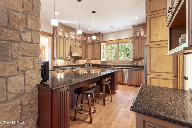 kitchen with exhaust hood, a kitchen breakfast bar, stainless steel dishwasher, decorative backsplash, and a center island