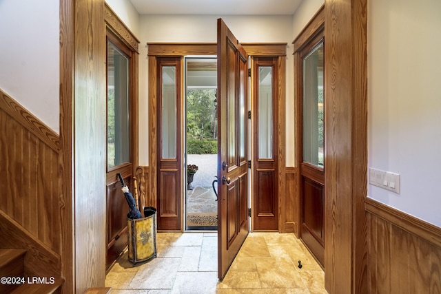 doorway with wainscoting and stone tile floors