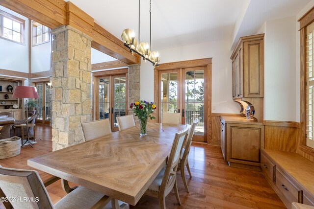 dining area with wainscoting, a chandelier, wood finished floors, and french doors