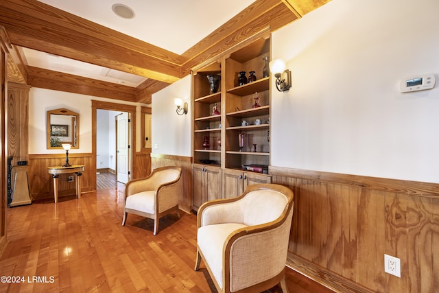 living area with wood-type flooring, built in features, beamed ceiling, and wainscoting