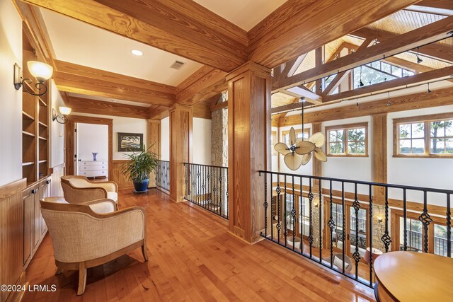 interior space with visible vents, wood walls, lofted ceiling with beams, and hardwood / wood-style flooring