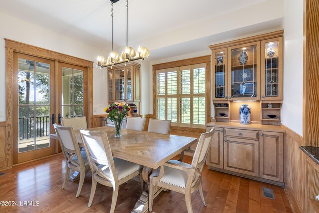 dining room featuring french doors, a notable chandelier, visible vents, light wood-style floors, and wainscoting