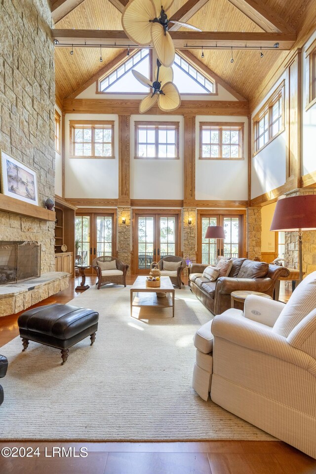 living area with french doors, a fireplace, beam ceiling, and wooden ceiling