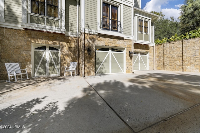 exterior space with stone siding, an attached garage, and driveway