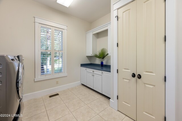 laundry area featuring cabinet space, light tile patterned floors, baseboards, visible vents, and washer and clothes dryer