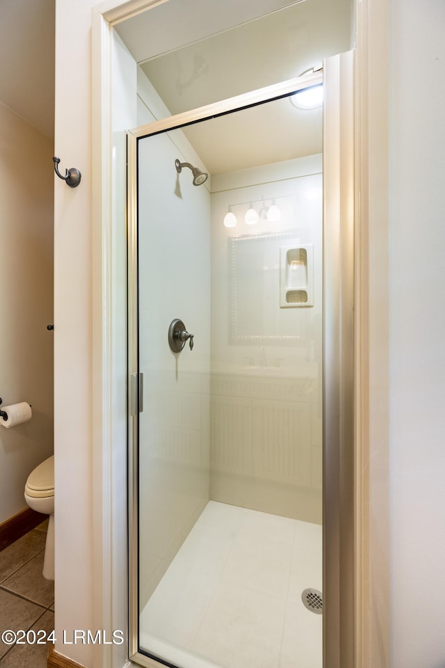 bathroom featuring tile patterned flooring, a shower stall, and toilet