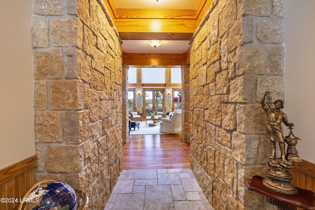 hallway with a wainscoted wall and stone tile floors